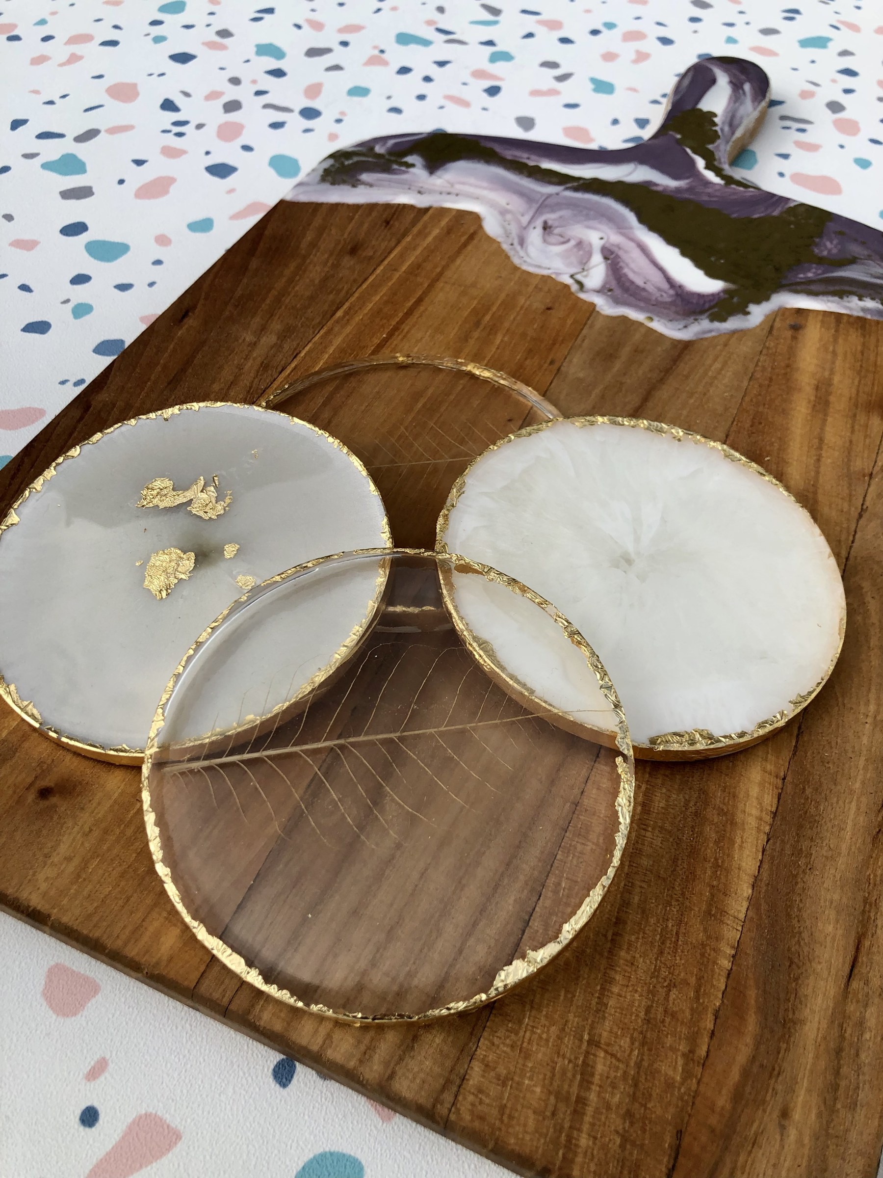 Gold-edged marble effect resin coasters on a walnut serving board