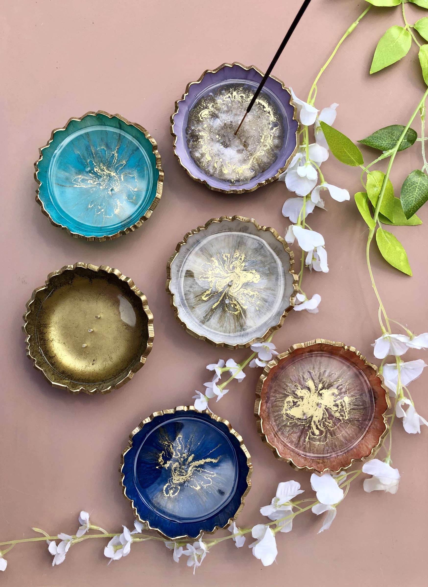 Collection of coloured resin incense holders styled with white blossoms